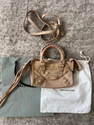 Trendig snygg unik Balenciaga mini city bag - Otroligt fin väska. Påse och dustbag ingår, obs har inget kvitto kvar dessvärre. Se skicket på bilder, den har varit väl omhändertagen och är i mycket fint skick, men har några mindre defekter samt skinnet och guldnitar har normalt slitage ( skriv för fler bilder på detta, då man bara får ha 7 bilder här). 