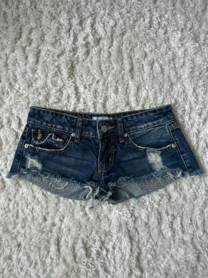 Mörkblå jeansshorts från Revice - Säljer ett par mörkblå jeansshorts från Revice med slitna detaljer och råa kanter. De är i 32 men passar som xs. Perfekta för sommaren💕