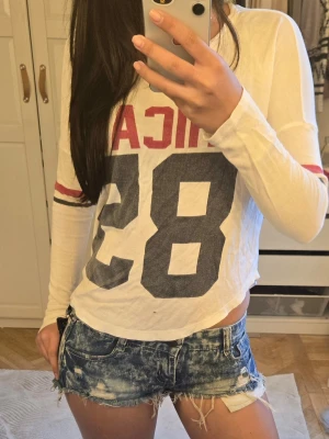 Blå slitna jeansshorts - Säljer ett par blåa lågmidjade jeansshorts med slitna detaljer samt cool fick design. Vintage men ändå väldigt bra kondition 💕 storlek xs-s