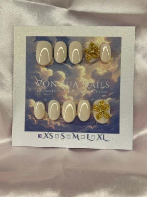 GoldieGlow (XS);ExtraShortOval  - Snygga handgjorda press-on naglar i beige med glansig finish. Två av naglarna har handgjorda 3D-blommor i guld som ger en lyxig och unik touch. Extra korta i en Oval form i XS: 14 mm, 11 mm, 11,5 mm, 10 mm, 8 mm, perfekta för dig som vill ha något extra.