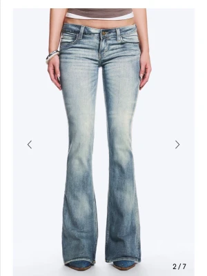 Blå bootcut jeans från Cheap Monday - Säljer ett par ljusblå bootcut jeans från Cheap Monday med snygg slitning och klassisk femficksmodell. Jeansen har en låg midja och ett stort vitt logomärke bak i linningen. Tillverkade i denim med stretch för skön passform.