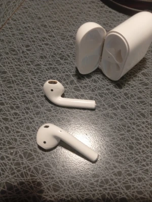 Vita trådlösa hörlurar från Apple - Säljer ett par vita trådlösa in-ear hörlurar från Apple med tillhörande laddningsetui. Hörlurarna har en stilren och minimalistisk design i blank plast och passar perfekt för musik, samtal och poddar. Laddningsetuiet är kompakt och lätt att ta med. 