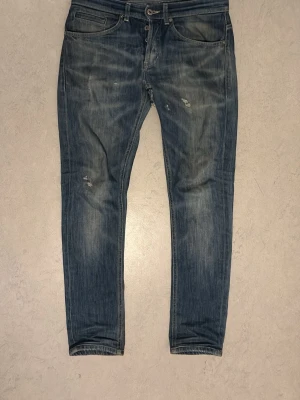Blåa Don Dup George Jeans - Snygga blå slim fit jeans från Don Dup med slitningar på låret och knät. Jeansen har klassisk femficksmodell, knappgylf och lätt tvättad look. Perfekta för en avslappnad och trendig stil. Den ända defekten är ett litet hål vid skrevet som går att sy eller lägga lapp över, annars ingen defekt.