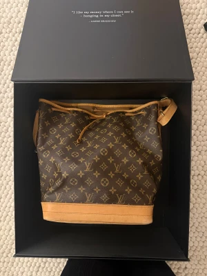 Louis Vuitton Monogram Canvas Noe GM handväska - Väskan köpt på ARetroTale av mig 2026-02-19. Mycket bra skick invändigt och utvändigt. Se defekt på bild 7, mycket vanligt på denna modell. Medföljer dustbag från ARetroTale, digitalt certifikat, kvitto, etiketter som syns på bild 2. Storleken är dator vänlig. B 26 cm X H 34 cm X D 20 cm. 