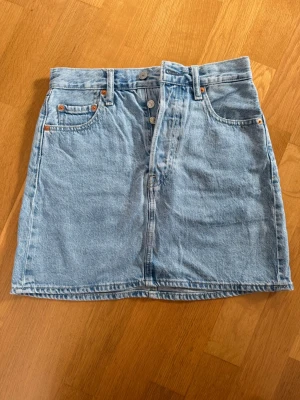 Ljusblå jeanskjol från Levi's - Levi’s ljusblå jeanskjol med knappgylf. Nästan oanvänd. Stl. 26. Köparen betalar frakt. 