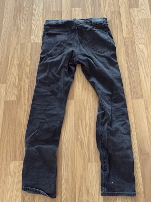 Svarta jeans från Lee - Säljer ett par svarta jeans från Lee med klassisk femficksmodell och raka ben. Jeansen har en diskret Lee-logga på bakfickan och är tillverkade i mjukt denimtyg som sitter snyggt. Perfekta för dig som gillar en enkel och stilren look.