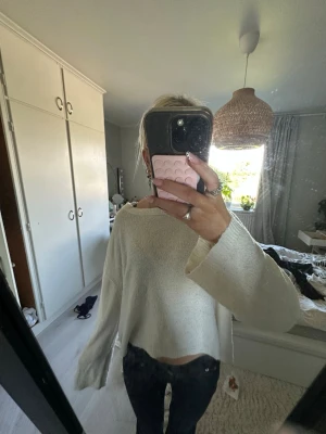 Vit croppad stickad tröja - Säljer en vit croppad stickad tröja med breda, långa ärmar och avslappnad passform. Tröjan har en enkel design utan synliga detaljer och är perfekt för dig som gillar en clean och chill stil. Passar till både jeans och kjol.