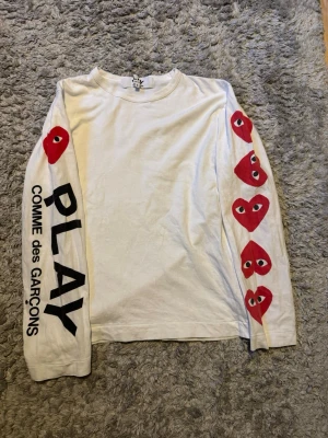 Play COMME des GARCONS longsleeve - Säljer en vit longsleeve från COMME des GARCONS. Den har inga hål eller så men den är lite nopprig. Storlek S passar XS. Självklart äkta 