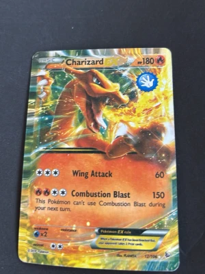 Charizard EX Pokémonkort - Säljer ett Charizard EX Pokémonkort med 180 HP och attacker som Wing Attack och Combustion Blast. Kortet har en färgstark och glansig design med Charizard i eldig pose. Perfekt för samlare eller Pokémonfans.