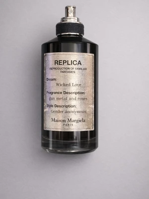 Maison Margiela Wicked Love parfym - Maison Margiela Wicked Love är en parfym i en svart glasflaska med metallisk etikett. Doften beskrivs som gun metal och rosor, och flaskan har en stilren, modern design med sprayfunktion. Märket är känt för sina unika och kreativa doftkombinationer.