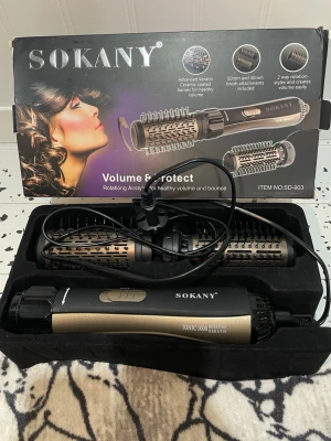 Sokany roterande varmluftsborste - Roterande varmluftsborste från Sokany i svart och guld med två utbytbara borstar (50mm och 40mm). Perfekt för att skapa volym och skydda håret med keramiska borsthuvuden och jonfunktion. Levereras i originalförpackning med sladd.