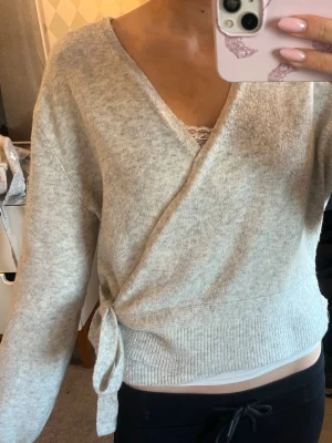 Ljusgrå omlottstickad tröja - Ljusgrå stickad omlotttröja från &other stories, storlek M men skulle säga mer S