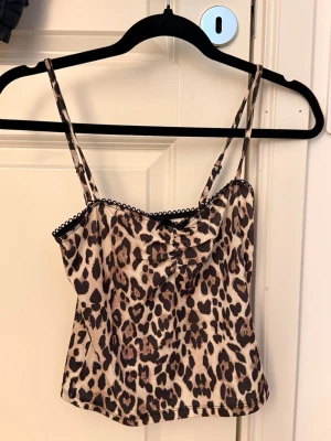 Leopardmönstrad linnetopp med spets - Snygg leopardmönstrad linnetopp med tunna axelband och söt spetskant upptill. Toppen har en figurnära passform och är perfekt för dig som vill sticka ut. Materialet känns mjukt och lätt mot huden.