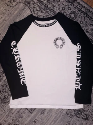 Chrome Hearts långärmad t-shirt - Säljer en svartvit långärmad t-shirt från Chrome Hearts med stora logotexter på båda ärmarna och tryck på bröstet. Sitter som M
