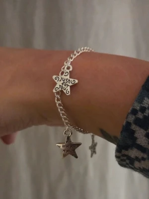 Silverfärgat armband med stjärnberlocker Rostfritt Stål  - Snyggt silverfärgat armband i rostfritt stål med kedja och två stjärnformade berlocker. Ena berlocken har texten 'just for you' och den andra 'love you'. Perfekt accessoar för att ge din outfit en personlig touch. Materialet är metall och armbandet har ett klassiskt karbinlås. Handgjort.