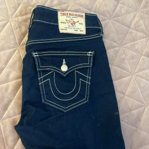 Mörkblå True Religion jeans - Snygga mörkblå jeans från True Religion med kontrasterande vita sömmar och ikonisk fickdesign bak. Förut var dem bootcut och jag har sytt ut dem lite så nu är dem typ en blandning mellan bootcut och flare