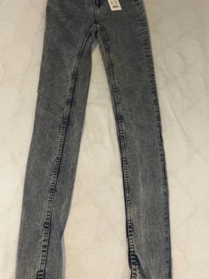 Grå tvättade skinny jeans 157 - Säljer ett par grå tvättade skinny jeans från 157 med hög midja och klassisk femficksmodell. Jeansen har en snygg vintagekänsla och är tillverkade i stretchigt denim för skön passform. Perfekta till en avslappnad streetstyle-look.