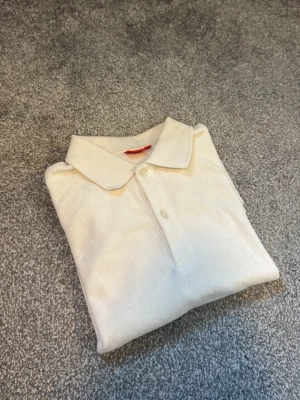 RYVLS pike - Klassisk vit piké skjorta med krage och två knappar framtill. Skjortan är tillverkad i mjukt bomullsmaterial och har en enkel, stilren design som passar till det mesta. Perfekt för dig som gillar en clean och tidlös look.