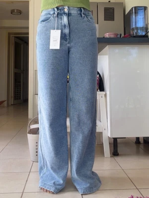 Good American jeans - Säljer ett par ljusblåa raka jeans från Zara med hög midja och klassisk femficksdesign. Jeansen har en avslappnad passform och är tillverkade i ett mjukt denimtyg. Perfekta för en trendig och bekväm look.