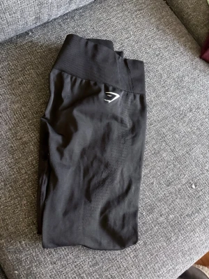 Svarta seamless leggings med Scrunch bak rumpan Gymshark - Säljer ett par svarta seamless leggings från Gymshark med hög midja och diskret logga framtill. Stretchigt material som sitter tight och bekvämt, perfekta för träning eller chill. Klassisk design utan synliga sömmar för en clean look.