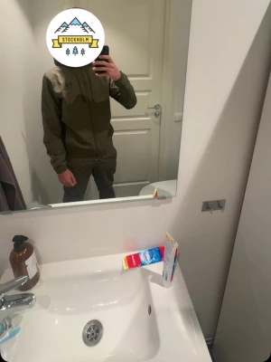 Olivgrön vindjacka från under armour  - Snygg olivgrön vindjacka från under armour  med dragkedja framtill och hög krage. Jackan har en minimalistisk design och diskret logga på bröstet. Perfekt för dig som vill ha en stilren och funktionell jacka till vardags.