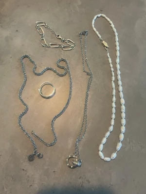Mix av silver- och pärlsmycken - Säljer ett set med smycken: två silverfärgade (Edblad)halsband, ett med cirkelberlock med stenar, ett chunky silverfärgat armband(äkta silver), en enkel silverring(levyr) och ett halsband med oregelbundna vita pärlor. Perfekt för dig som gillar att mixa olika stilar.