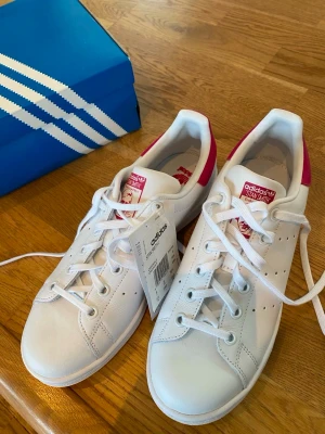 Adidas stan Smith junior sneakers  - Nya adidas skor köpta på hemsidan Joom men passade inte syskonet så säljer vidare! Storlek 39 och 1/3. Som sagt köptes de inte på adidas egen hemsida och det står att skorna är verifierade äkta från adidas, men kan därav inte säkerhetskälla att de är äkta! Ser dock identiska ut så svårt att avgöra ! Hursom är de oanvända (endast provade en gång) och köptes för 1100kr. Säljer för 950kr eftersom jag inte vet helt om de är äkta eller inte. Kan mötas i Stockholm och kan så sälja dem för 850kr! 