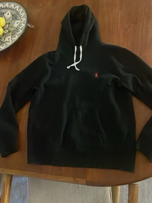 Svart hoodie från Polo Ralph Lauren - Säljer en svart Ralph lauren hoodie i storlek M men passar även som S. Hoodien är i väldigt bra skick och inga synliga defekter finns. Skriv vid fler frågor!!
