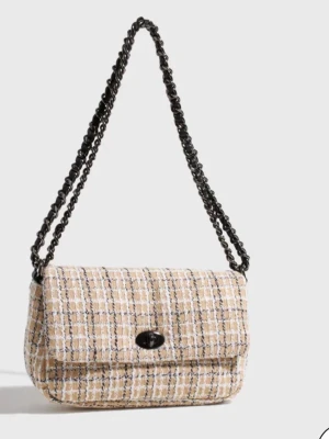Beige tweed axelväska med kedja - Trendig axelväska i beige och vit tweed med rutmönster och svarta detaljer. Väskan har en svart kedjerem och ett vridlås framtill.  Köptes för 849kr 