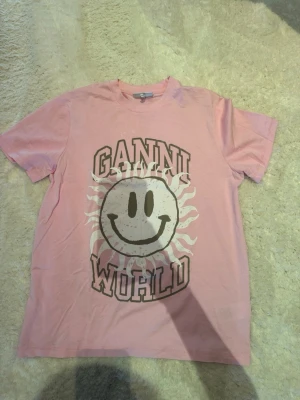 Rosa Ganni t-shirt med tryck - Säljer en rosa t-shirt från Ganni i storlek XS. Jag är 163 cm lång!