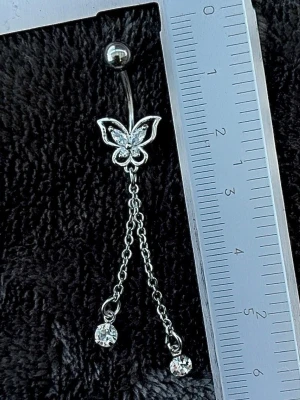 NY oanvänd Navelpiercing med hänge | Kirurgiskt stål | Fjäril, kedjor och vita stenar  - 💕30% Bundle-rabatt vid köp av minst 2 artiklar. ⭐️NY oanvänd piercing i kirurgiskt stål; rostfritt och säkert för läkta piercingar.                               📏MÅTT ⭕️Stavens längd: 10mm ⭕️Stavens tjocklek: 1,6mm ⭕️Smyckets totala längd: 60mm                                                                         🤍Färger: Silver och vit                                                            💌Skickas spårbart via Plick SafePay.