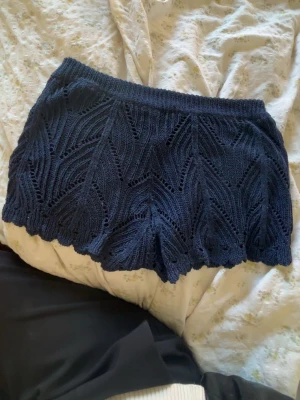 Mörkblå stickade shorts med mönster - Unika mörkblå stickade shorts med vågig kant och snyggt hålmönster. Perfekta för dig som vill ha något bekvämt och stilrent med en twist. Resår i midjan för skön passform och cool struktur.