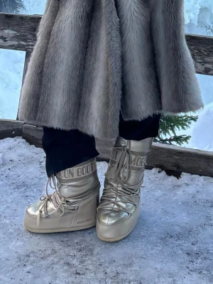 Guldiga Moon Boots med snörning - Säljer ett par guldiga Moon Boots med klassisk hög modell och snörning framtill! Storlek 39-41