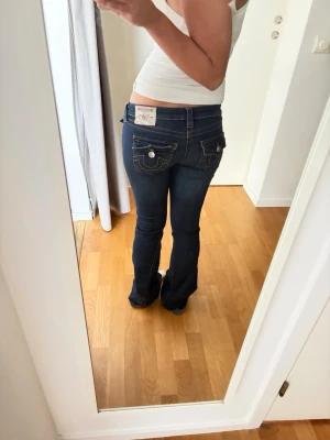 True Religion mörkblå bootcut jeans - Säljer ett par mörkblå bootcut jeans från True Religion i modellen JOEY. Jeansen har låg midja och flare nedtill. Storlek 25 i midja.