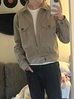 Anovair Travis Tank Jacka - En tvärfet nyköpt beige Anovair fieldjacka som endast är använd ett fåtal gånger. Nypris är 2427 kr och säljer halva priset, den är i helt nytt skick. Storleken är XS men den passar S och passformen är perfekt för dig som är mellan ~172 och 180 cm. Jag på bilden är 180 cm lång. Säljer då den inte kommit till användning så mycket som en så snygg jacka förtjänar. Det är bara att höra av dig om du är intresserad. 