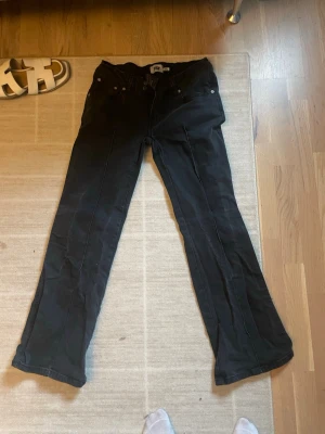 Svarta bootcut jeans från 157 - Säljer ett par svarta bootcut jeans från 157 med klassisk femficksdesign och silverfärgade nitar. Jeansen har normal midja och är tillverkade i ett stretchigt denimtyg som sitter snyggt. Perfekta för dig som gillar en tidlös och avslappnad stil.