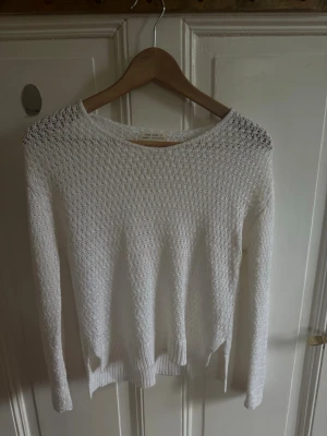 Vit stickad tröja från Zara Knit - Vit stickad tröja från Zara Knit med lång ärm och rund halsringning. Tröjan har ett luftigt, hålstickat mönster och ribbade muddar vid ärmslut och nederkant. Perfekt för lager-på-lager och en chill look.