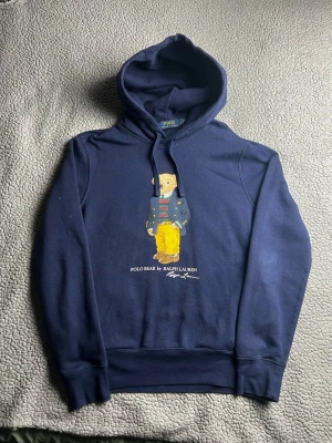 Mörkblå Polo Bear hoodie Ralph Lauren - Snygg mörkblå hoodie från Ralph Lauren med den ikoniska Polo Bear-trycket på bröstet. Mycket bra skick. Skickar snabbt efter att du har beställt. Frågor? Skicka ett meddelande.