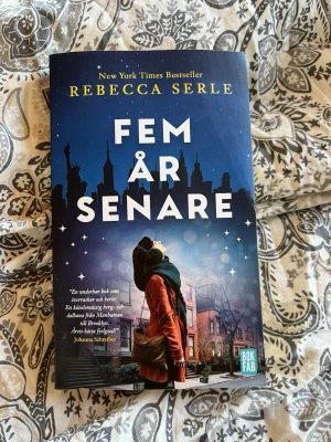 Fem år senare av Rebecca Serle - En pocketbok med titeln 'Fem år senare' av Rebecca Serle. Omslaget är blått med en stadssilhuett och en person i röd kappa. Boken är tryckt på papper och har ett modernt, tilltalande omslag. Perfekt för dig som gillar romantisk och känslosam skönlitteratur.