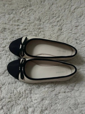 Beiga/svarta ballerinaskor - Jättesöta beiga ballerinaskor med svart topp och rosett💕de är i stl 37 från Graceland. Säljer då de är för små för mig. Endast använda en gång.