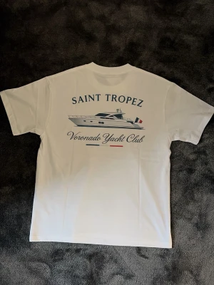 Voronado Yacht Club T-shirt  - Finns alla storlekar. Vit t-shirt från Voronado Yacht Club med tryck av en yacht och texten 'Saint Tropez' på ryggen. Framsidan har en liten logga på bröstet. Klassisk passform och rund hals. Perfekt för en stilren och avslappnad look.