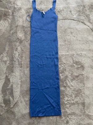 Blå långklänning från Dilvin - Snygg blå långklänning från Dilvin med smala axelband och ribbad struktur. Klänningen har en figurnära passform och är tillverkad i ett stretchigt material som känns bekvämt mot kroppen. Perfekt för dig som gillar en enkel men stilren look.