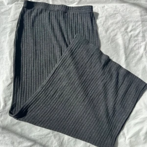 Mörkgrå ribbad långkjol från New Yorker - Säljer en mörkgrå långkjol från New Yorker i ribbad bomullsmix. Kjolen har en rak passform och elastisk midja med slits längst ner. Perfekt till en avslappnad vardagslook eller när du vill vara extra cozy.