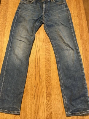Riktigt schyssta Lee Jeans - Ett par blå Lee jeans med rak passform och klassisk femficksdesign. Jeansen har en lätt tvättad look och är tillverkade i denim. Perfekta för en avslappnad stil och passar till det mesta.