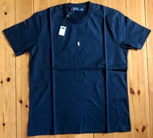 Marinblå t-shirt från Polo Ralph Lauren - Snygg marinblå t-shirt från Polo Ralph Lauren med klassisk passform och korta ärmar. T-shirten har en liten broderad logga i vitt på bröstet och är tillverkad i mjuk bomull. Perfekt för en stilren och enkel look.