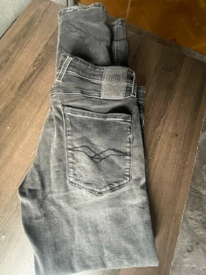 Svarta slim fit jeans från Replay - Snygga svarta slim fit jeans från Replay med klassisk femficksdesign och diskret logga på bakfickan. Jeansen har en lätt tvättad look och är tillverkade i ett mjukt bomullsmaterial med stretch för extra komfort. W32 L32