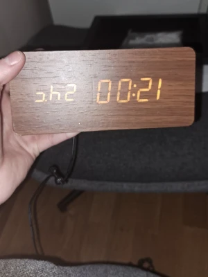 Digital träklocka med LED-display - Snygg digital klocka med trälook och gul LED-display. Visar tid och har en rektangulär form. Perfekt som modern inredningsdetalj till skrivbordet eller nattduksbordet. Drivs med sladd och har minimalistisk design.