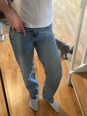 Blå raka jeans med hög midja - Säljer ett par ljusblå raka jeans med låg midja. Jeansen har en avslappnad passform och är tillverkade i denim. Perfekta för en casual och trendig look.
