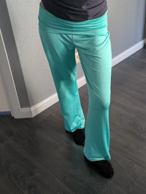 Teal pants - Säljer ett par turkosa eftertraktade foldover yogapants perfekt för sommaren! Byxorna är tillverkade i ett mjukt och stretchigt material som känns skönt mot huden. Passar mig som har 79 cm i innerbenslängd, mäter man är det 75 men de blir lite längre då man har dom lowwaist