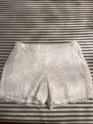 Vita spets-shorts från amisu - Säljer ett par superfina vita shorts från Amisu i storlek 38. De är täckta med vacker spets och har en elegant look. Perfekta för sommarens alla fester eller en dag på stan. De har en bekväm passform och är i nyskick.
